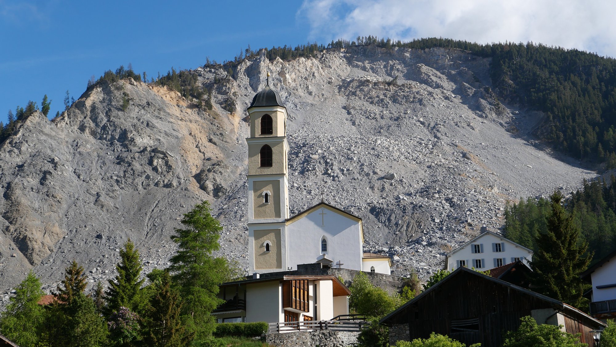 View of the church in Brienz/Brinzauls against the backdrop of the debris cone left by the 2023 rockslide